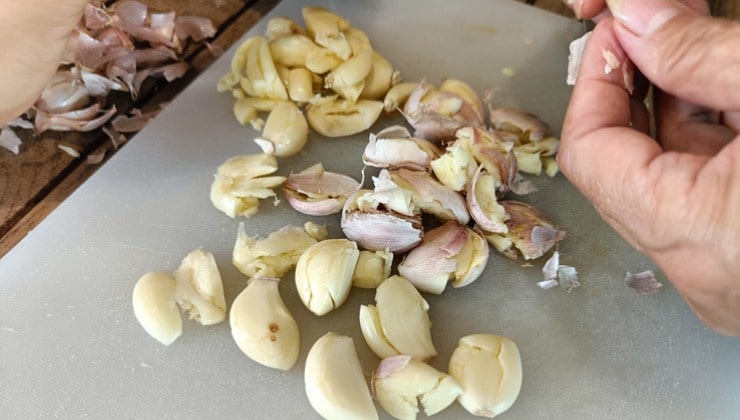 Mujer pela ajo sobre tabla de cortar